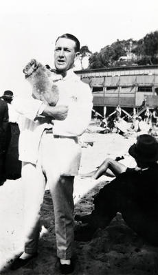 Man holding a koala with Manly Surf Club in the background