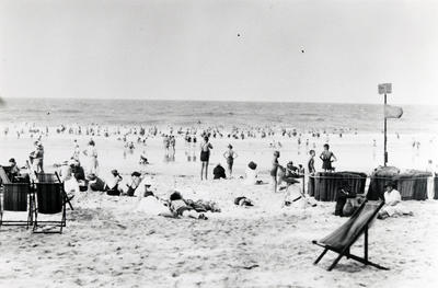 crowded beach with deck chair in front