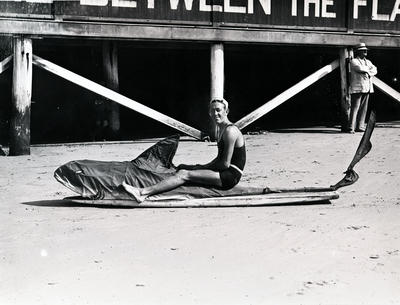 Young man seated astride a mock shark in the front of the surf pavilion