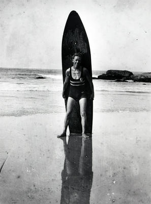 Young man leaning against a surfboard