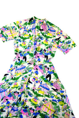 Printed cotton seersucker beach dress with pattern of circus theme in pink, green, blue,black and yellow. It has short sleeves, lapels at front neck but no collar and half circle skirt. It has slit pockets just below the waist but the belt is missing.