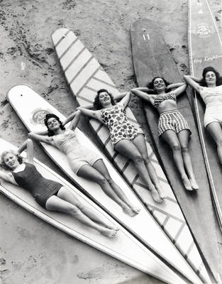 5 girls in swimwear lying on long wooden boards of Manly Life Saving Club