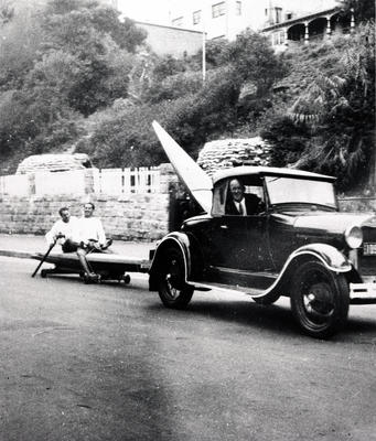 Taking the boards to Freshwater'. one man in car with board in back, two men being towed.