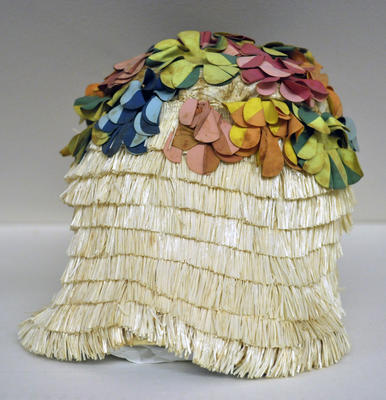 Rubber cap decorated with raffia and yellow orange green blue pink fringerubber flowers , pointed crown of coloured flower contour over ears suction rim inside machine made