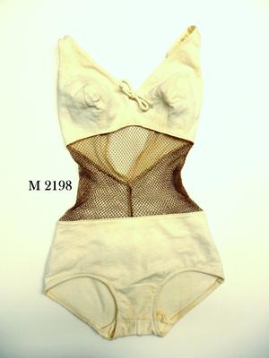 Cream one piece, nylon and net bikini-like top attached to pants by net, low v back, Cole of California brand. Padded, lace bra with tied bow at bust. Low V back. Similar example: MO1066.