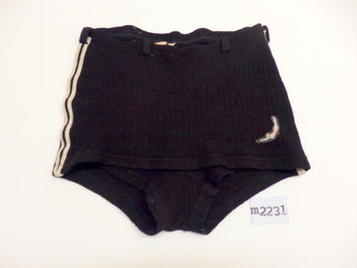 Black ribbed wool swimming trunks. Double white lines down sides, skirted front. Woollen black belt loops and Jantzen logo on LHS. Size 30, Made in Australia.