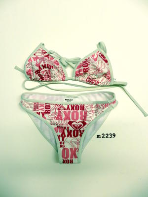 Roxy light pink, dark pink and white bikini. Design includes Roxy logo, Roxy name and the words, 'the heart of surfing'. Top has triangle shape bust with string ties. Bottoms are high cut briefs.