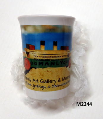 MAG&M souvenir ceramic mug with colour print of wooden Manly ferry with the by-line, 'Manly Art Gallery and Museum..Seven miles from Sydney, a thousand miles from care..'