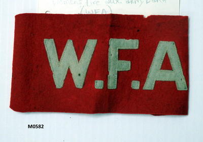 Women's fire aux arm band. Red felt with white felt letters 'W.F.A.' sewn on. Ties of white cotton hand and machine made.