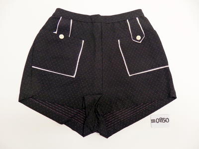 Black purple spotted rayon shorts, white piping around square front pockets and around tabs joining waistband & pocket with white button, rear zipper & button opening, machine sewn, S:25