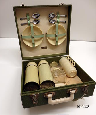 Picnicset suitcase vocered in green leather look canvas with white spots overall contains two thermos 4 bakelite cups/saucers 2 glass jars with cream bakelit lids 4 teaspoons w bottle openers 1 tin