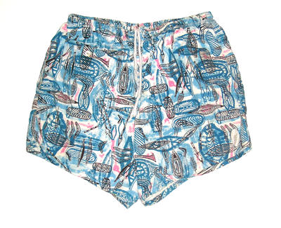 Blue printed cotton swimming shorts with black aboriginal patterns elastic waist drawstring tie pocket with button RHS machine sewn. Lined with cotton, pattern features boomerang, woomera,spears in black, blue, pink and white.