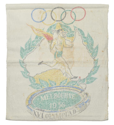 White cotton. 1956 Melbourne Olympic print on front with torch bearer image & Olympic rings. Green, gold, blue, red & black band effect near top & bottom seams