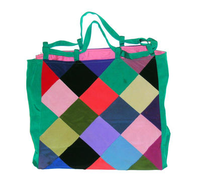 beach bag of multi coloured quilted Lycra squares with green side gussets and green strap held in place by green loops. Lined with pink cotton, the base stiffened with heavy cardboard