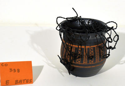 black pot with terracotta carved design, jute top