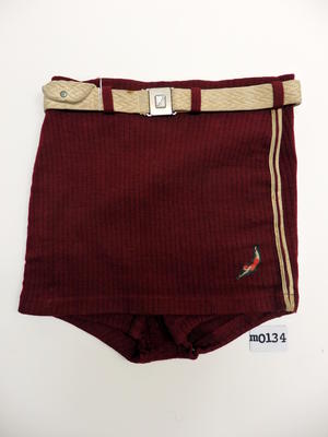 Maroon woollen trunks with skirt front, cream trim of double cotton cord down each side, cream cotton belt with key pouch and metal square buckle with embossed 'Jantzen' logo, 'Jantzen' label and logo LHS, high cut sides 35.5cm