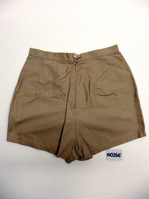 Beige cotton shorts, zipped at front, button attached with elastic, two darts each side, front peaked pockets at back. Machine made