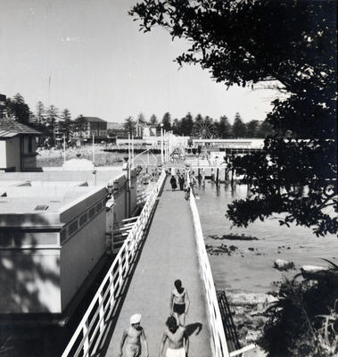 East along the boardwalk of the harbour pool past the pavilion, towards Manly Wharf and Manly Fun Pier