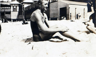 George Pike, member of Manly Surf Club, at Manly Beach, with the Surf Club Pavilion in the background