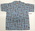 Pale blue cotton printed with yellow, red and black flag deign. One chest pocket, short sleeves, double stitching, blue buttons, revere neck. Size 22.